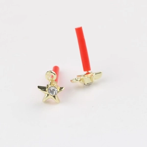 Detail of star-shaped gold earrings with zircon inlay and red needle protectors