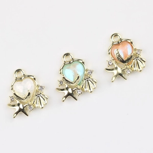 Macro detail of ocean themed heart charms with fishtail, starfish and shell accents