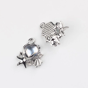 Detailed macro view of silver fishtail shell charms with iridescent heart stone inlay