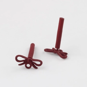 Detailaufnahme matter weinroter Ohrstecker in Schleifenform mit glatter Oberfläche