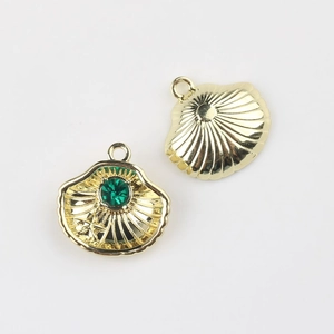 Detailed view of gold shell pendants with green zircon and starry texture for DIY jewelry