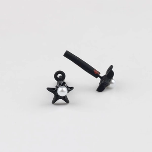 Detailed view of matte black star earrings with inlaid white pearls and tube components