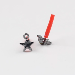 Macro detail of black star earrings with embedded round gemstone and metallic luster