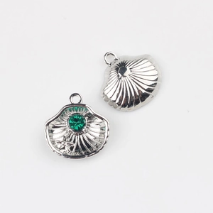 Detailed view of shell charm with green rhinestone and star texture in silver finish