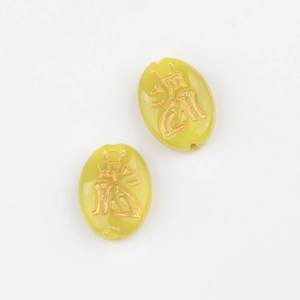 Macro shot of oval Czech glass beads in light green with golden dragon character carving