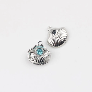 Macro detail of silver scallop shell pendant with blue rhinestone inlay for DIY jewelry