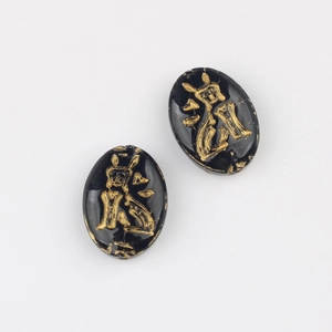 Detail of oval black Czech glass beads with gold engraved characters for DIY jewelry