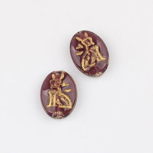 Macro detail of oval purple Czech glass beads with gold gilded cat and flower engravings