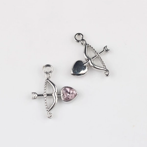 Detail showing front and back of silver Cupid bow and arrow charms with pink heart zircon