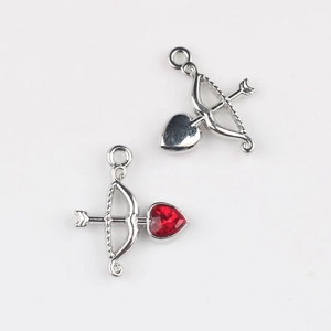 Detailed view of silver alloy Cupid arrow pendants with red heart zircon for DIY jewelry