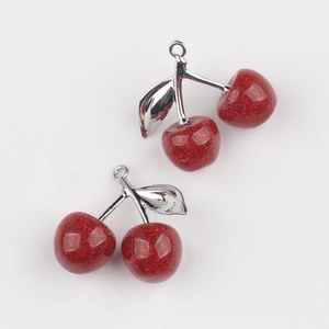 Detailed close-up of glittery red cherry pendants with silver alloy leaves for DIY jewelry