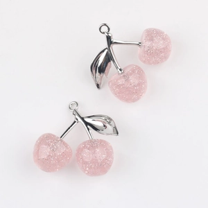 Close-up of pink glitter resin cherry pendants with silver leaves for DIY jewelry
