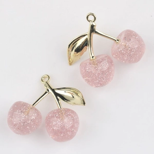 Detail view of cherry charms with pink glitter resin and golden metal loops for jewelry DIY