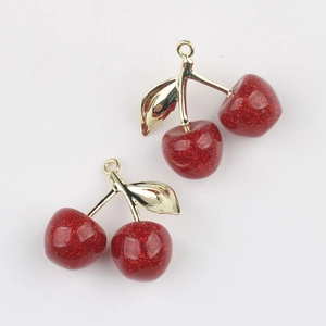 Macro detail of red glitter cherry charms with golden leaves for jewelry making