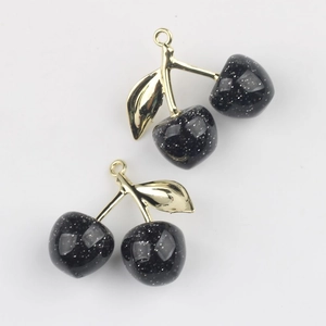 Detailed macro view of black glitter cherry pendants with gold leaves for DIY jewelry