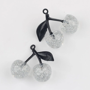 Close-up of DIY cherry charms with silver glitter resin fruit and black leaves detail