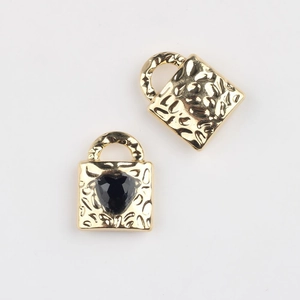 Detailed view of gold alloy heart-shaped lock pendants with textured lava finish and black zircon