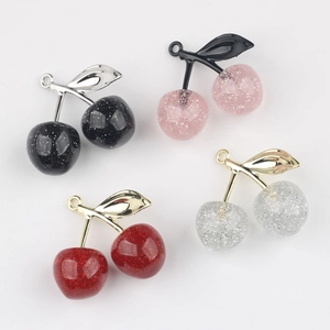 Detailed view of cherry pendants with glitter resin and metal leaves for DIY jewelry