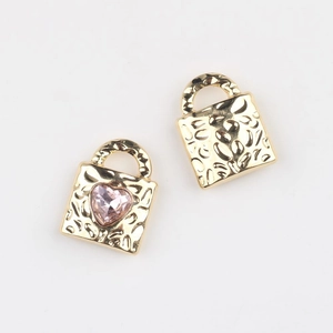 Detailed view of gold alloy heart-shaped lock pendants with pink zircon and hammer textures