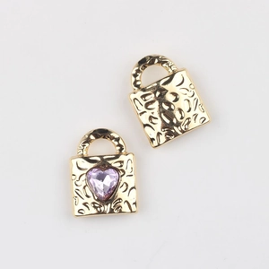 Detail of gold heart lock charms with hammered texture and pink cubic zirconia inlay