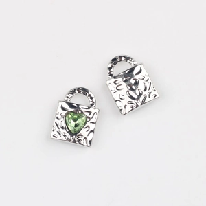 Detail of heart-shaped lock pendants with hammered metal texture and green zircon stone