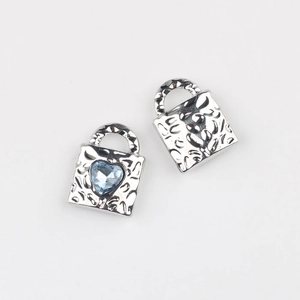 Macro shot of silver hammer-textured lock charms with heart-shaped blue zircon inlay