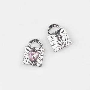 Detail of heart lock charms with hammered texture and pink zircon for DIY jewelry