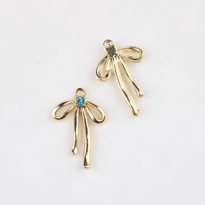 Détail de breloques nœud dorées avec zircon bleu et anneaux pour bijoux faits à la main