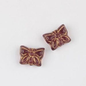 Detailed close-up of dark red glass butterfly beads with vintage gold gilded wing patterns