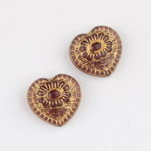 Detail of heart-shaped Czech glass beads with gold floral engraving for DIY jewelry