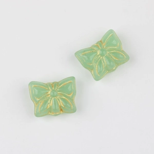 Macro shot of two mint green glass butterfly beads with detailed golden gilded edges