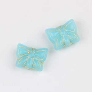 Macro detail of blue glass butterfly beads with vintage gold rim for DIY jewelry