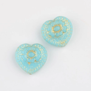 Detail of blue glass heart beads with gold floral carvings for DIY jewelry making