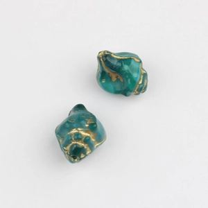 Macro shot of peacock green conch-shaped glass beads with vintage gold foil gilding