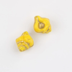 Detail of yellow conch-shaped glass beads with gold-painted edges for DIY jewelry
