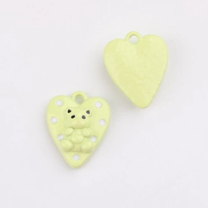 Macro view of heart-shaped light green alloy pendant with 3D bear and white dots