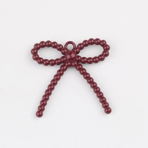 Detalle de un colgante de lazo con cuentas rojo oscuro y anillo para joyería artesanal