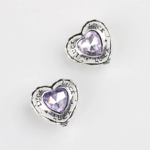Detailed macro of heart charms with luck engraving and purple zircon inlay