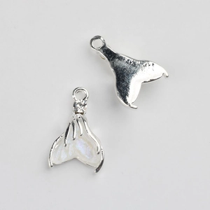 Detailed macro view of silver alloy mermaid tail pendants with white pearlescent resin