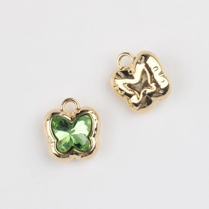 Detailed view of butterfly charms with green crystal inlays and golden alloy finish