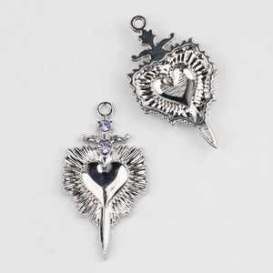 Detailed view of silver heart and sword pendants with purple zircons for jewelry making