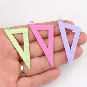 Three colorful triangle ruler pendants in green, pink, and purple held in a hand