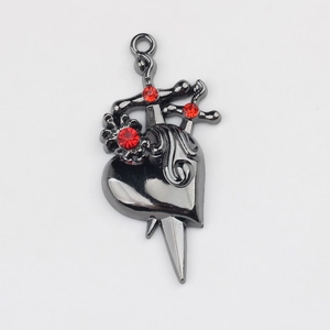 Macro detail of gothic dagger heart charm in gunblack alloy with red rhinestones