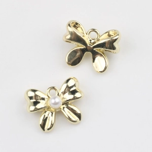Detalle de colgantes de lazo dorado con perlas blancas para creación de joyas DIY