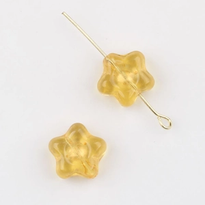 Detail of yellow Czech glass star beads with gold gilded finish and metal pins for DIY jewelry