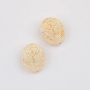 Detailed macro of vintage white Czech glass beads with gold embossed rose relief patterns