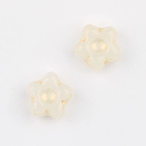 Macro detail of cream star-shaped glass beads with vintage gold gilded edges and center