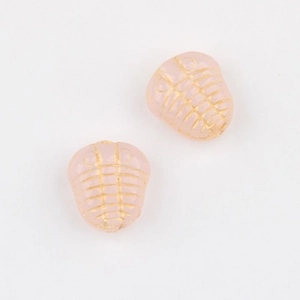 Dettaglio di perline rosa a forma di trilobite con incisioni dorate per bigiotteria