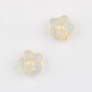 Close-up of star-shaped frosted glass beads with golden accents for jewelry making