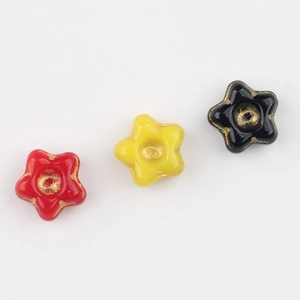 Macro detail of red, yellow and black star-shaped glass beads with gold gilded edges